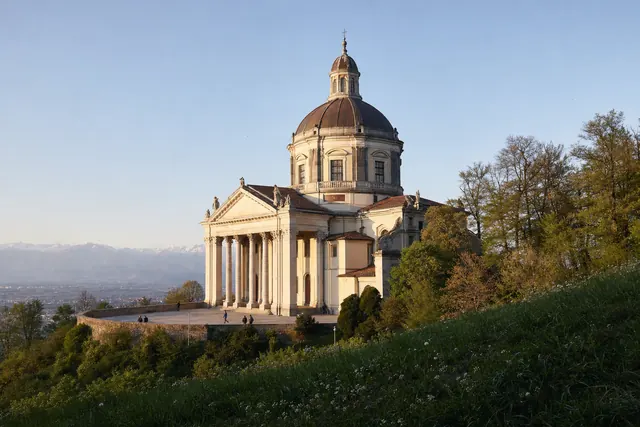 Basilica barocca con grande cupola e pronao sulla cima di una collina boscosa (immagine creata con AI)
