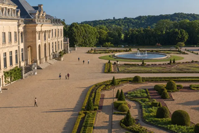 Corte di un palazzo barocco che si apre su un giardino formale con siepi e fontana (immagine creata con AI)